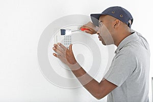 Security consultant fitting burglar alarm sensor in room