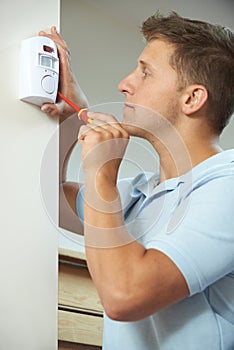 Security Consultant Fitting Burglar Alarm Sensor In Room