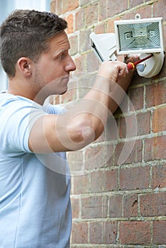 Security Consultant Fitting Security Light To House Wall