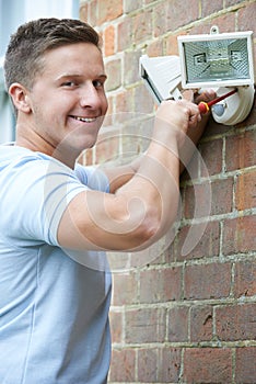 Security Consultant Fitting Security Light To House Wall