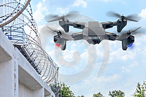 Security drone patrols the territory across the sky. Guarding the wall with barbed wire drone with blue and red beacon photo