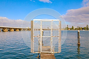 Security gate on small jetty for mooring boat in Wallis Lake with Forster-Tuncurry bridge in background