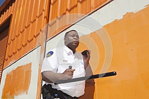 Security Guard With Baton Using Walkie Talkie