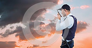 Security guard gesturing and talking on walkie talkie while facing towards sky