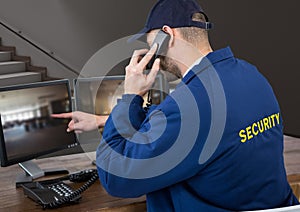 Security guard in his office phoning and pointing something in the screen