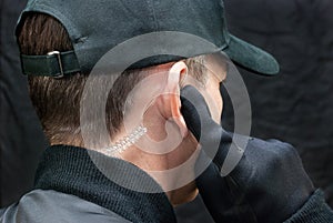 Security Guard Listens To Earpiece, Over Shoulder