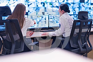 Security guard monitoring modern CCTV cameras in surveillance room. Two Female security guards in surveillance room