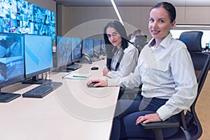 Security guard monitoring modern CCTV cameras in surveillance room. Two Female security guards in surveillance room. Smiling into