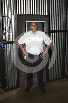 Security Guard Standing At Corrugated Metal Doorway