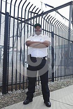 Security Guard Standing In Front Of Prison Fence