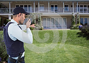 Security guard talking on radio while pointing at house