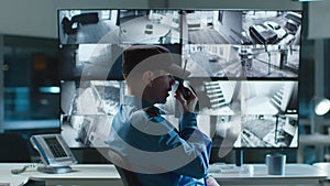 Security guard talking on walkie talkie while looking at cctv camera footage on multiple computer screen