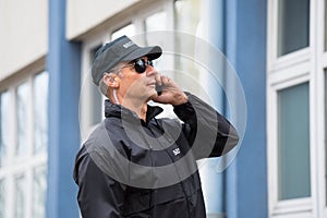 Security Guard Using Mobile Phone Outside Building