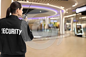 Security guard using portable radio transmitter in shopping mall