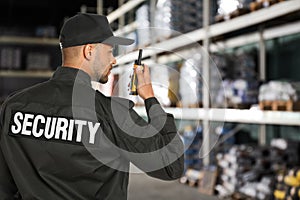 Security guard using portable radio transmitter in wholesale warehouse