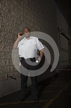 Security Guard Using Walkie Talkie While Patrolling At Night