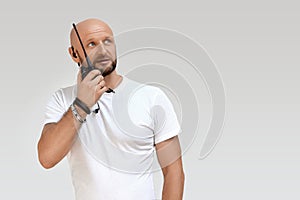 A security guard with a walkie-talkie, a bald 40-year-old man talking on a walkie-talkie, isolate