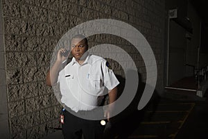 Security Guard With Walkie Talkie And Torch Patrols At Night photo