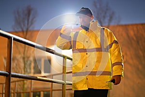 Security Guard Walking Building Perimeter With Flashlight