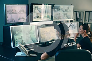 Security guards monitoring modern CCTV cameras in surveillance room