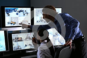 Security guards monitoring modern CCTV cameras in surveillance room