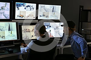 Security guards monitoring modern CCTV cameras in surveillance room