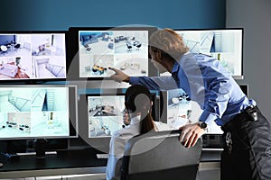 Security guards monitoring modern CCTV cameras in surveillance room