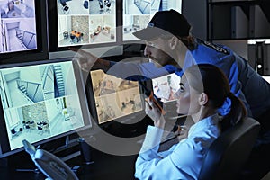 Security guards monitoring modern CCTV cameras in surveillance room