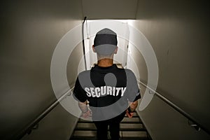 Security guy with a black hat and a uniform walking down the stairs inside a building