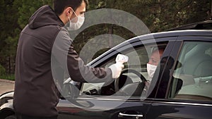 Security guy measures a driver`s body temperature and allows him to continue