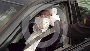 Security guy measures a healthy driver`s body temperature with thermometer