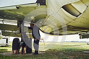 Security officer and detection dog inspecting aircraft at aerodrome