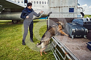 Security officer and drug detection dog checking luggage in airport