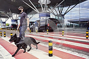 Security officer with police dog crossing the road at airport