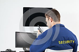 Security officer talking on walkie-talkie while looking at computer monitors