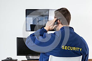 Security officer talking on walkie-talkie while looking at computer monitors