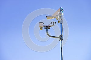 Security video camera and wind indicator against sky