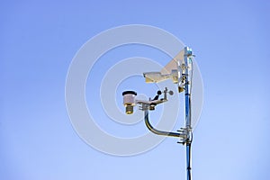 Security video camera and wind indicator against sky