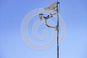 Security video camera and wind indicator against sky