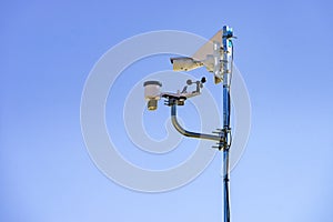 Security video camera and wind indicator against sky