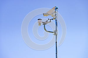 Security video camera and wind indicator against sky