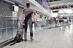 Security worker with detection dog patrolling airport terminal