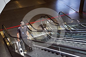 Security worker with detection dog using escalator at airport