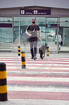 Security worker with police dog crossing the road at airport