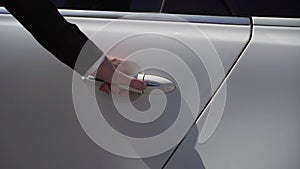 Sedan auto driver opening rear door of white luxury limousine vehicle.