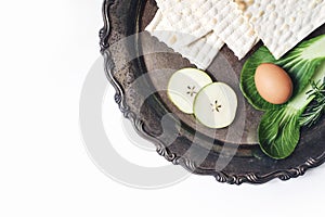 Seder dinner composition. Matzo bread, egg, apple fruit and chazeret lettuce vegetable on vintage silver tray. Happy