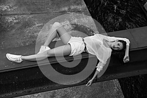 Seducing woman in summer clothes lying at abandoned building