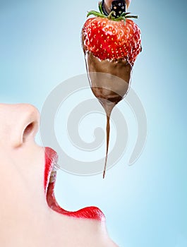 Seduction - red female lips eating chocolate strawberries photo