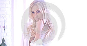 Seductive Blond Woman in White Looking at Camera