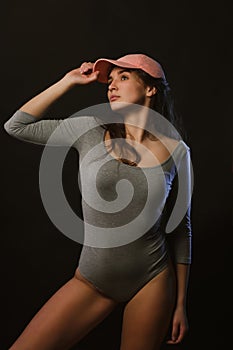 Seductive brunette girl posing in studio during model tests dressed in grey underwear and cap